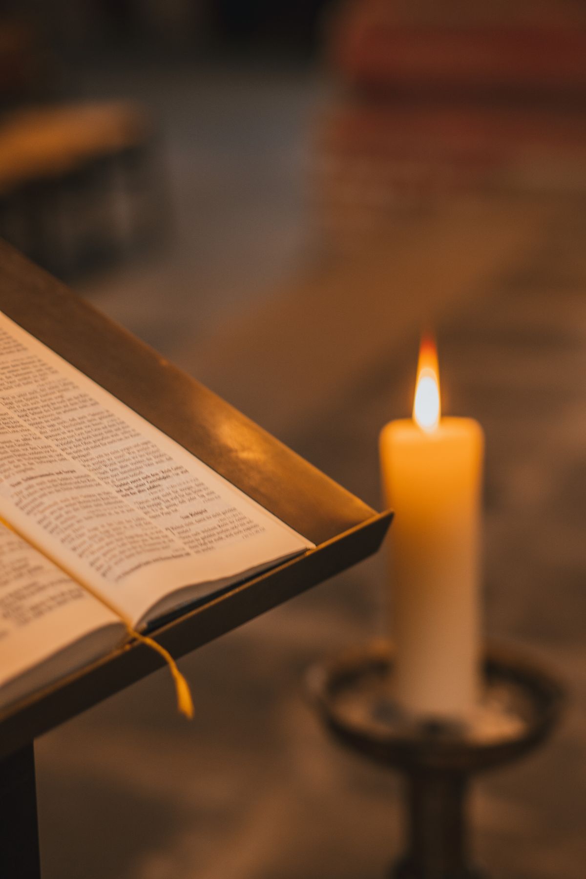 Open Bible beside a candle on the pulpit